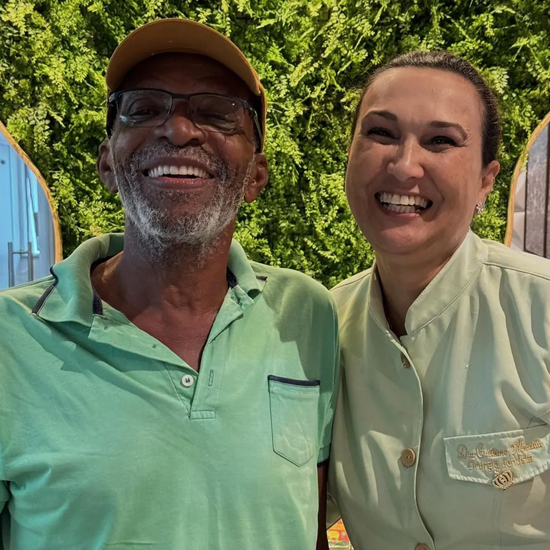 Paciente sorrindo ao lado da Dra. Cristiane Almeida no consultório em Salvador