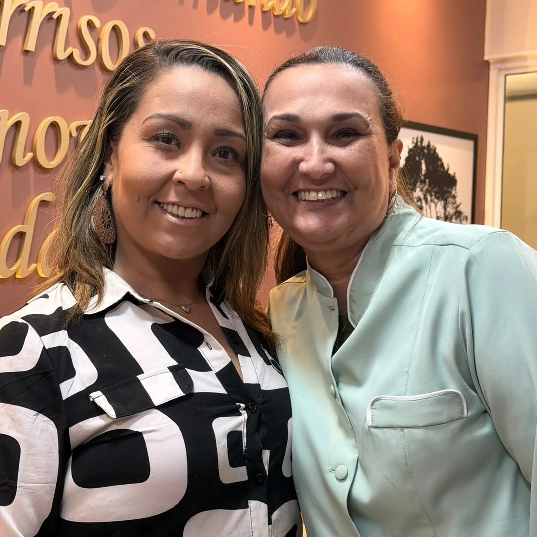 Paciente sorrindo ao lado da Dra. Cristiane Almeida no consultório odontológico.